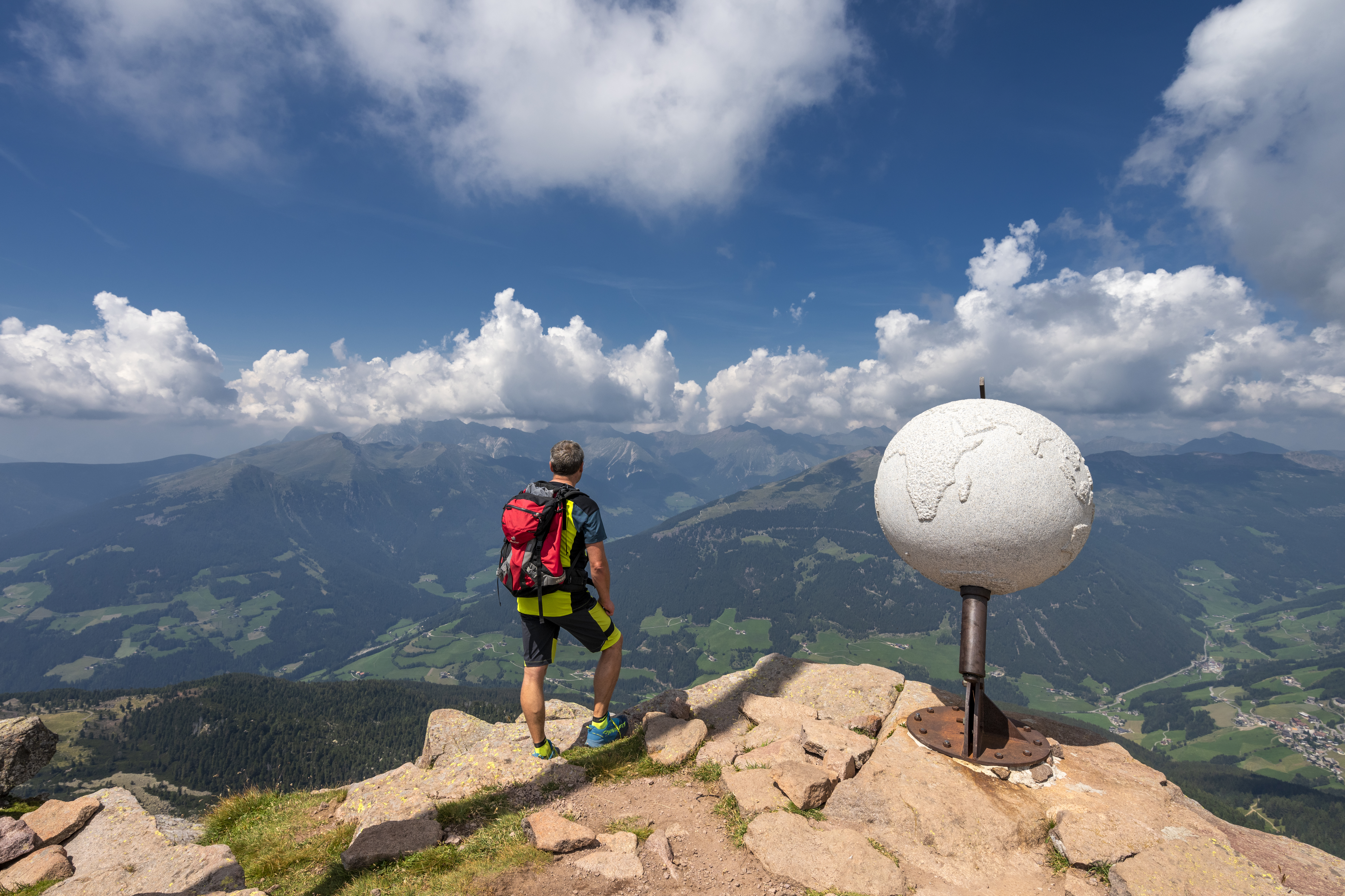 Man die over een landschap uitkijkt met een wereldbol naast zich