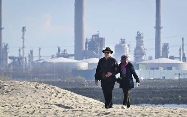 Een ouder stel loopt door de haven van Rotterdam, met de olie industrie bij de Europoort op de achtergrond