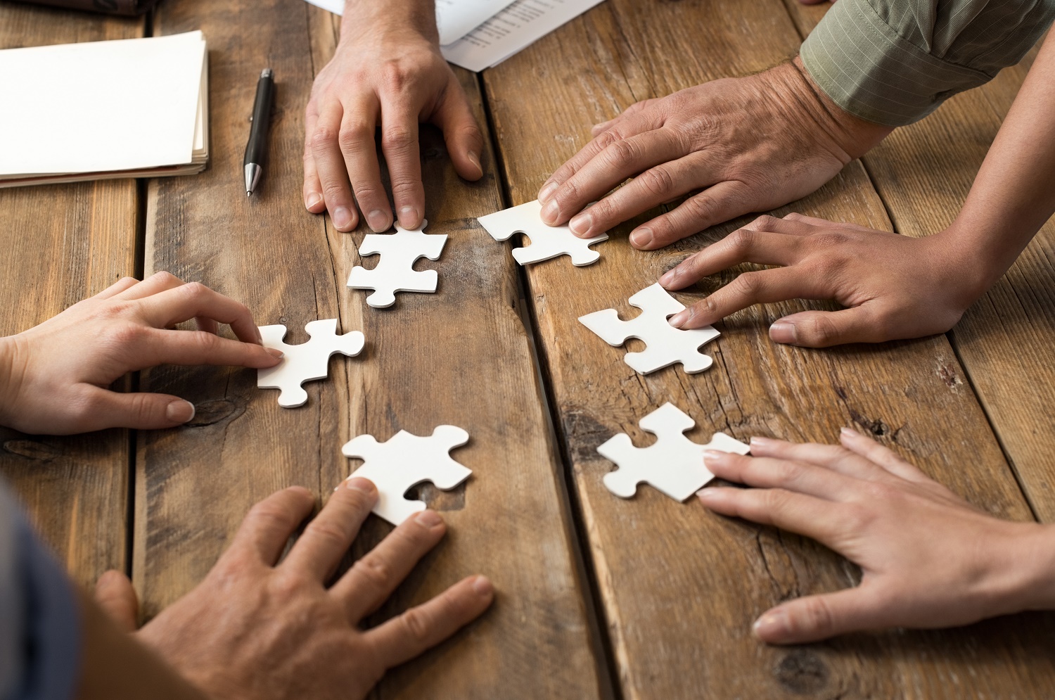 Handen schuiven puzzelstukjes naar elkaar toe 