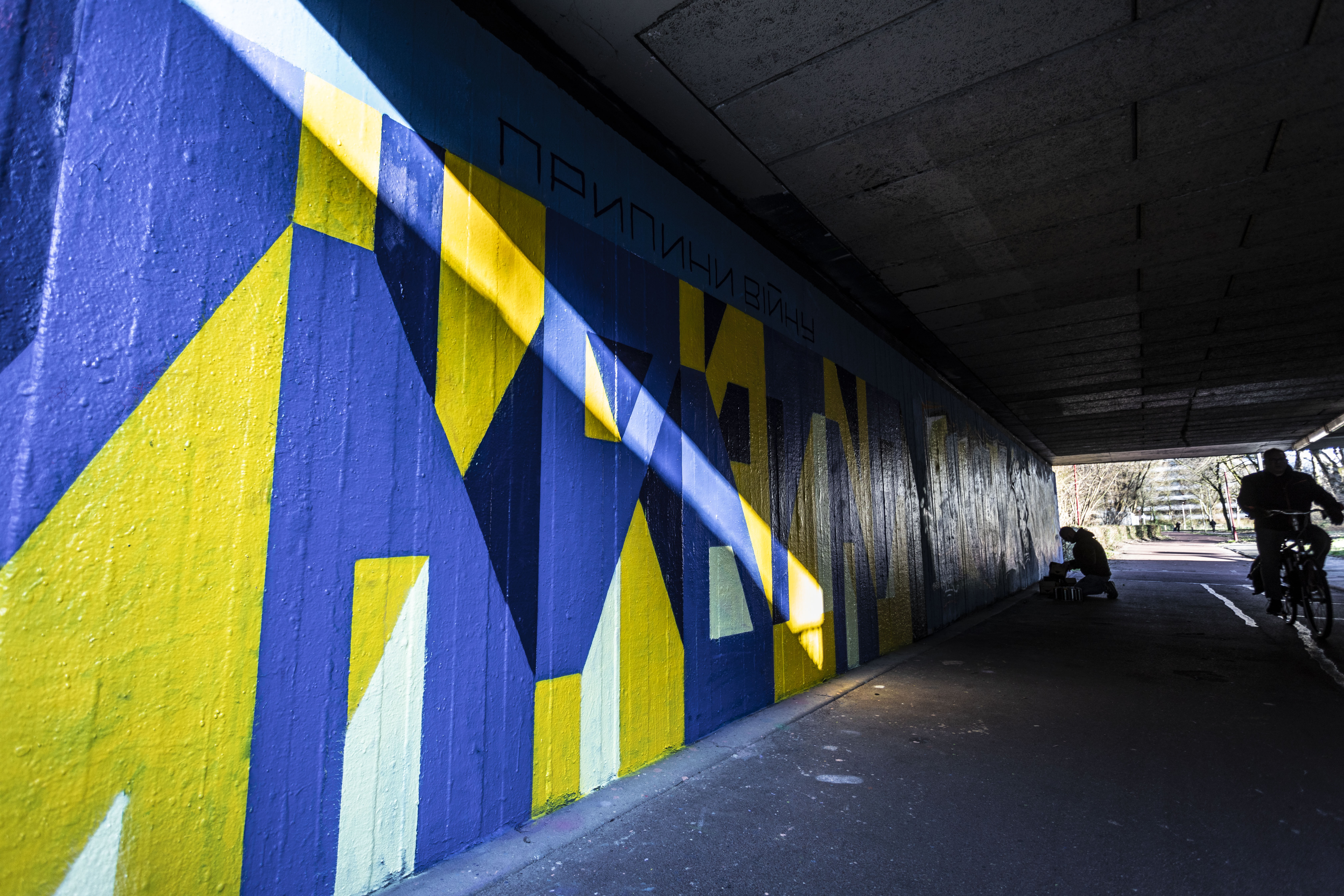 Straatkunst (legale graffiti muur) met de kleuren blauw en geel om aandacht te vragen voor de oorlog in Oekraïne