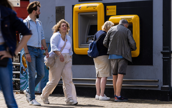 Mensen pinnen bij een pinautomaat van geldmaat in Delft