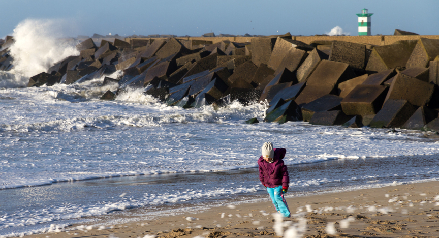 Meisje loopt tegen harde wind in bij pier Scheveningen