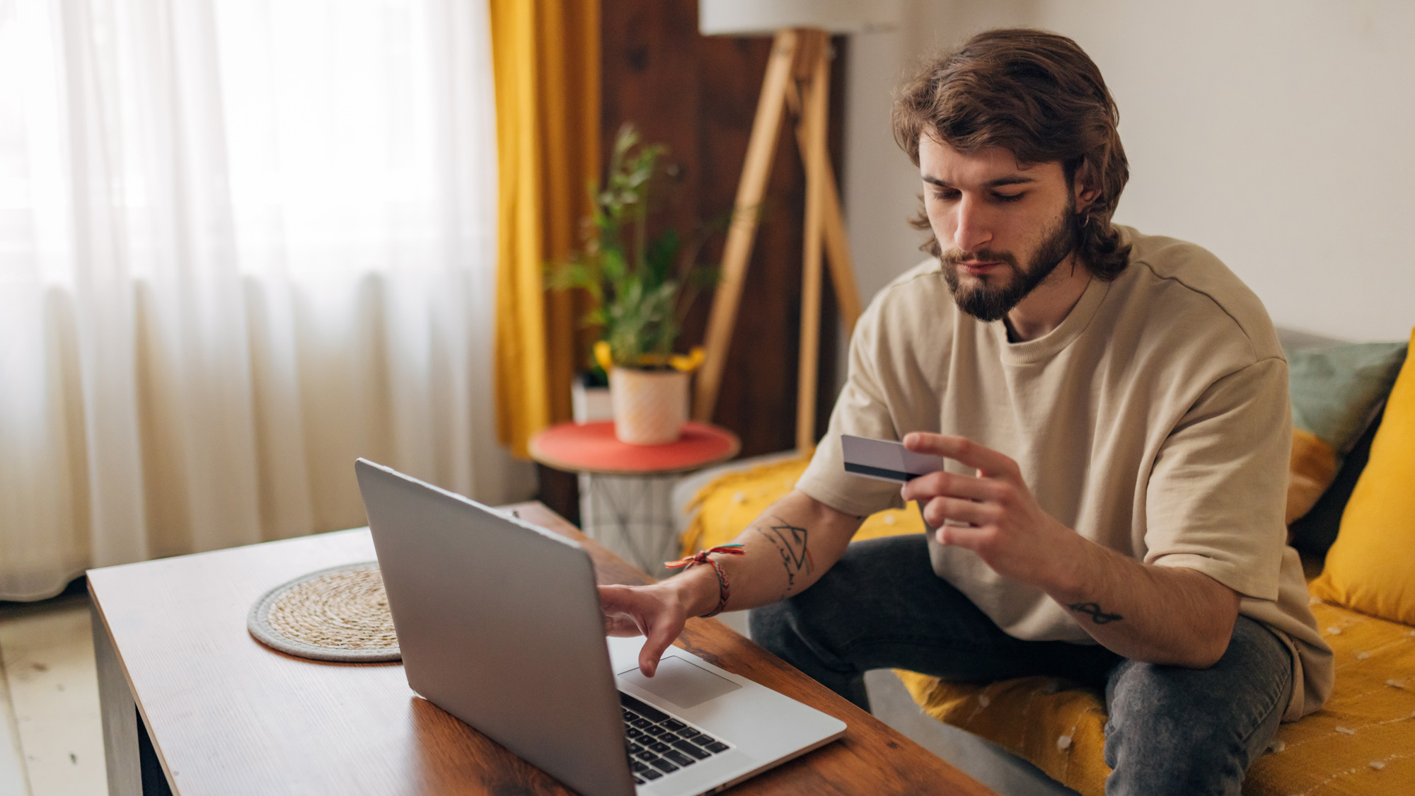 Een man zit achter zijn laptop en heeft problemen met zijn creditcard.