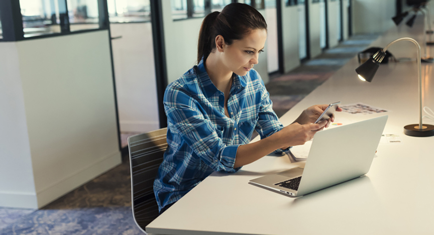 Vrouw op kantoor met computer en telefoon