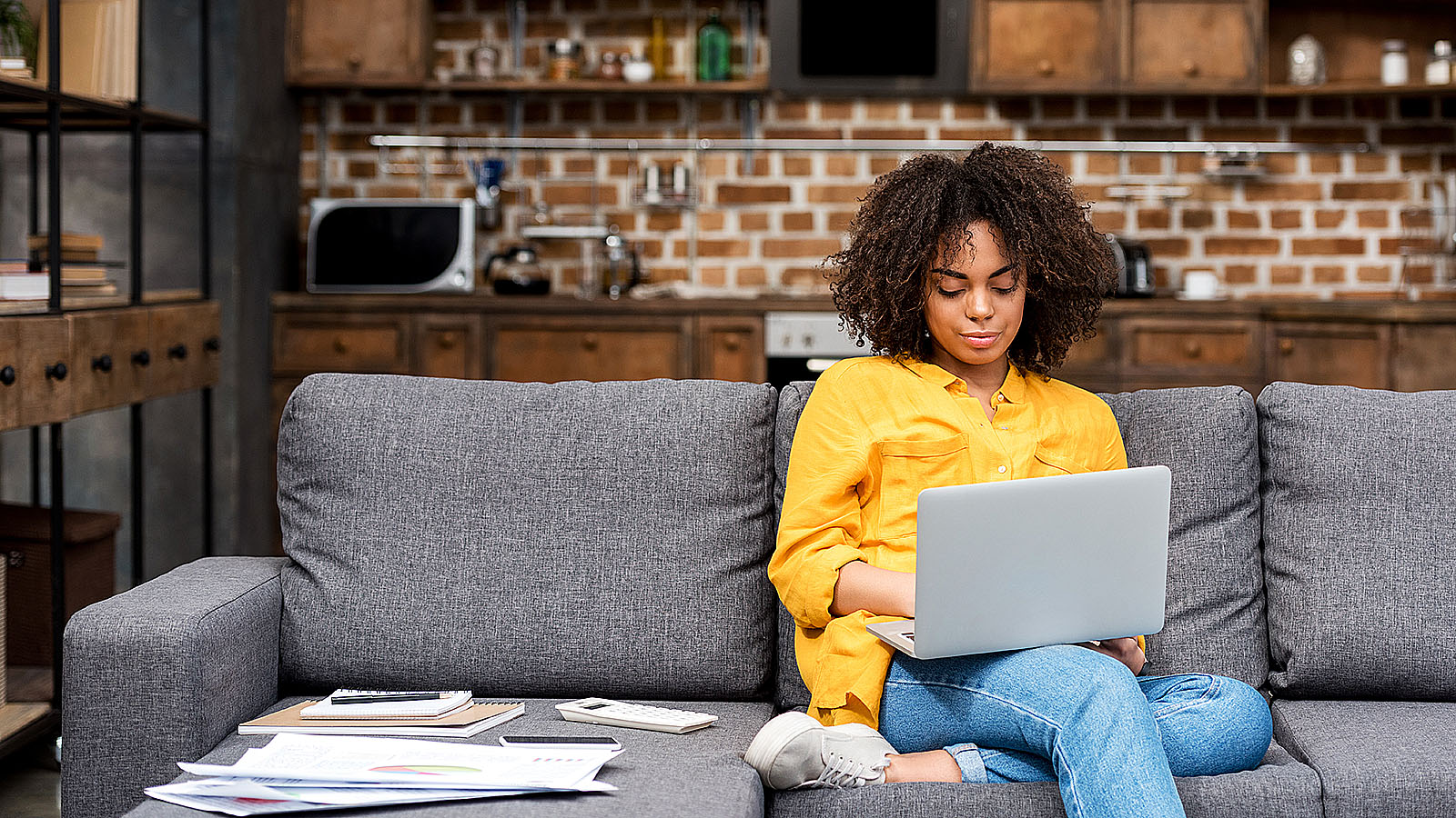 Vrouw zit op de bank met laptop op schoot