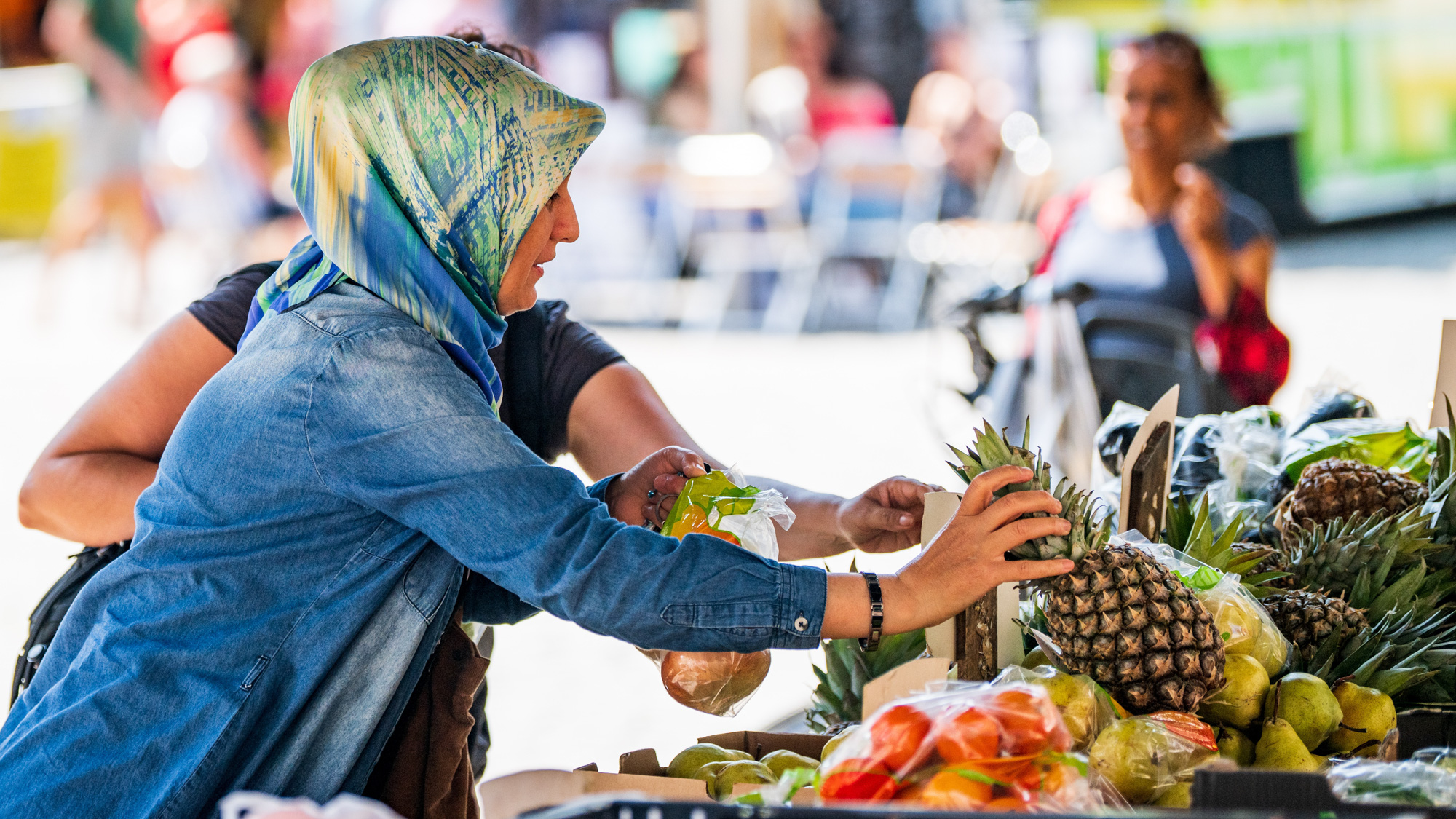 Vrouw koopt een ananas bij een groentestal.