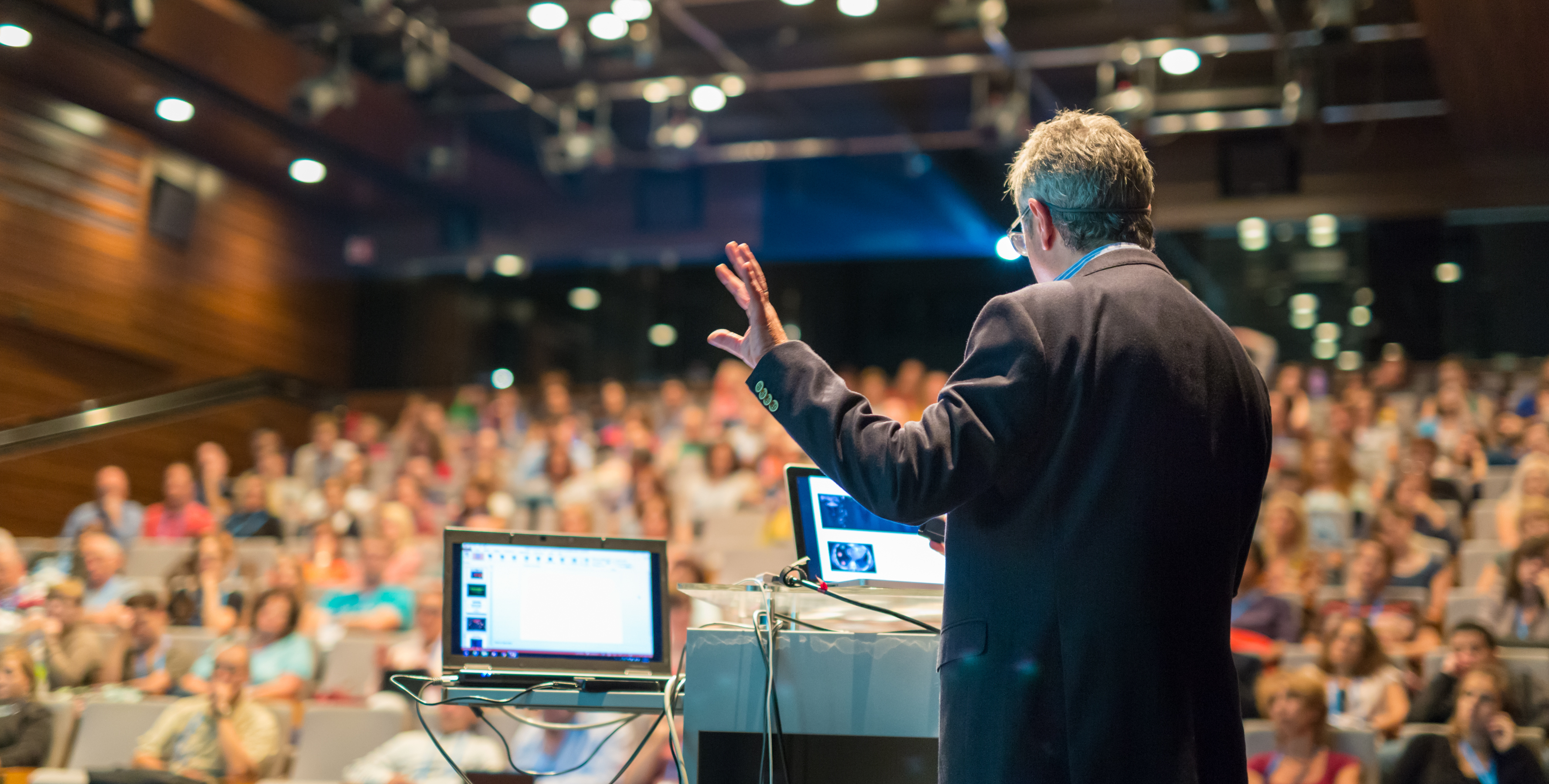 Spreker die een lezing geeft voor publiek in een conferentiezaal.