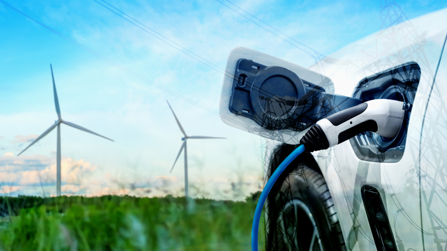 Elektrische auto staat in een weiland met windmolens.