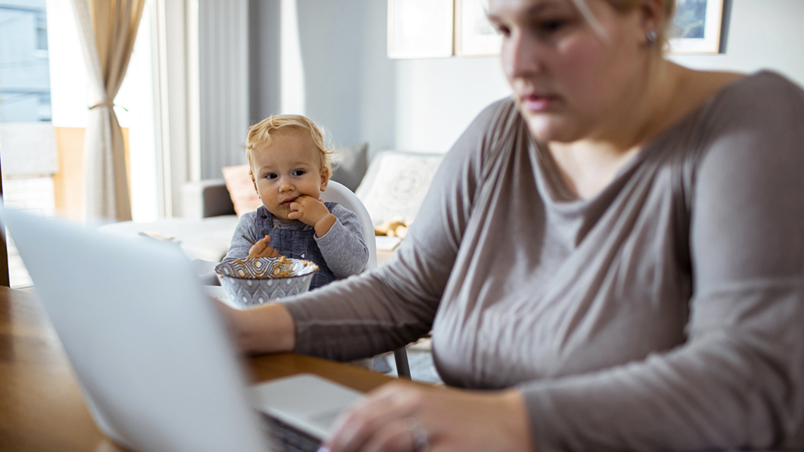 Vrouw met peuter kijkt op laptop
