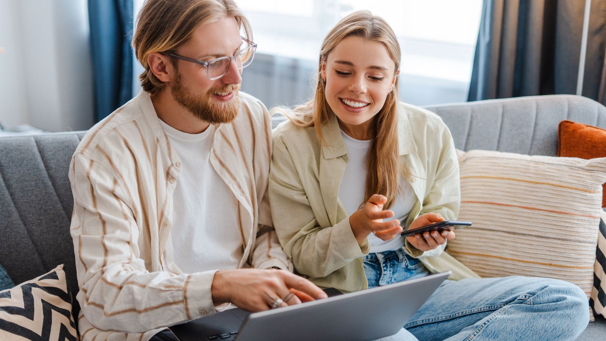 Een stel zit samen op de bank en doet een betaling op de laptop