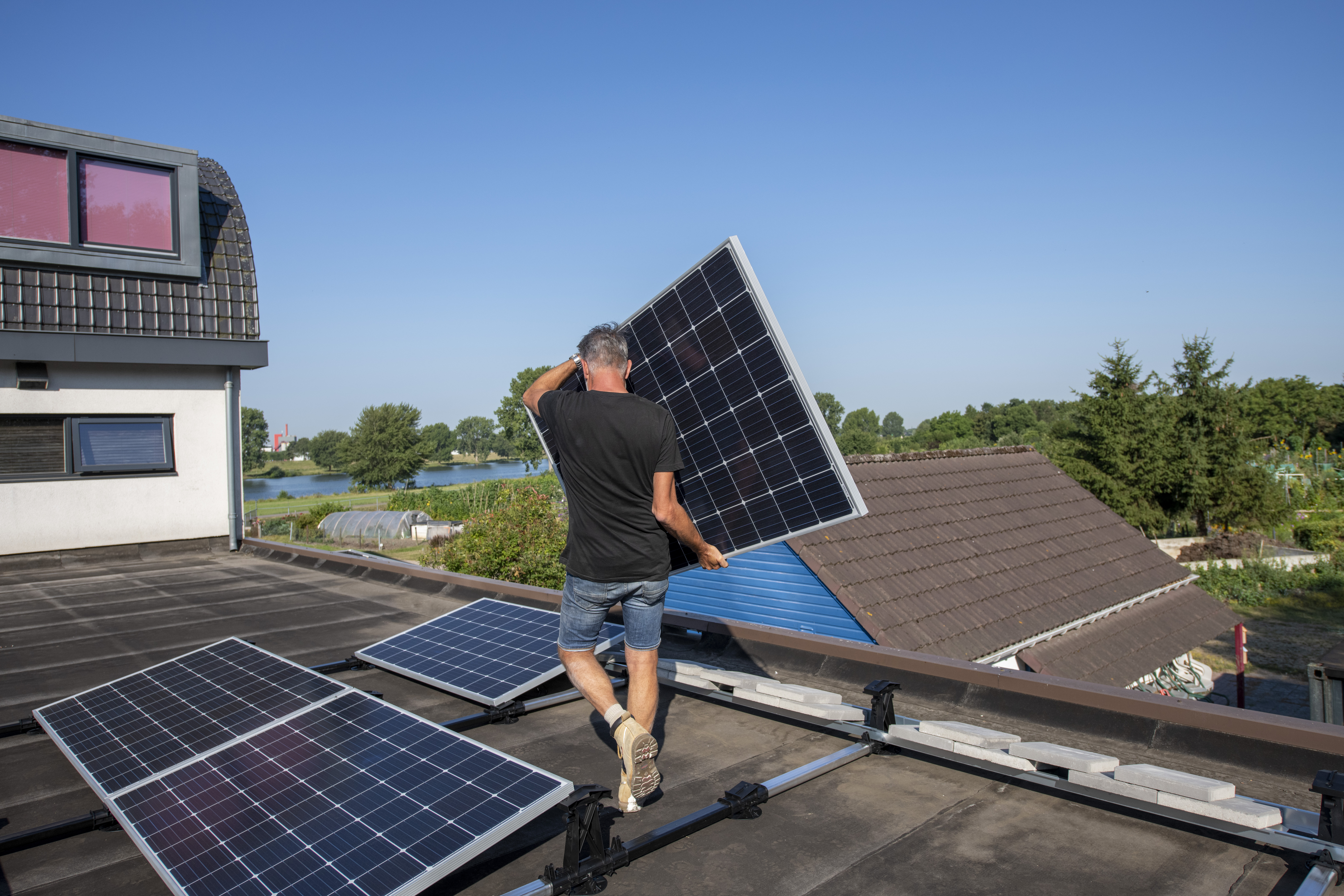 Man plaatst zonnepaneel op dak van woning