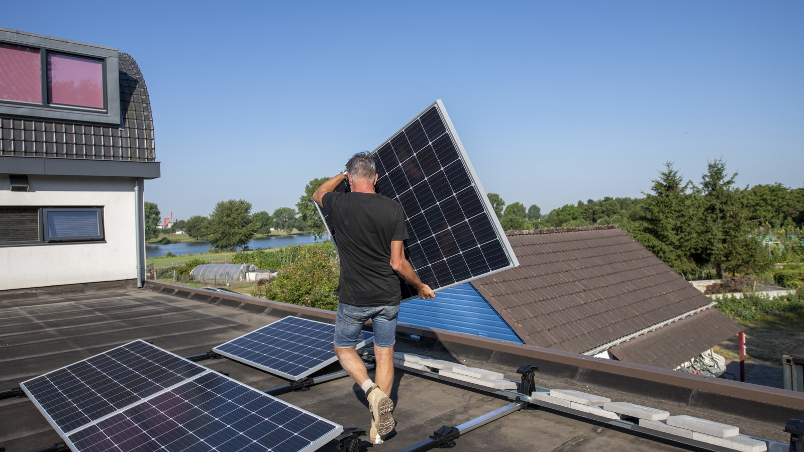 Man plaatst zonnepaneel op dak van woning