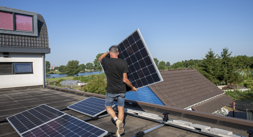Man plaatst zonnepaneel op dak van woning
