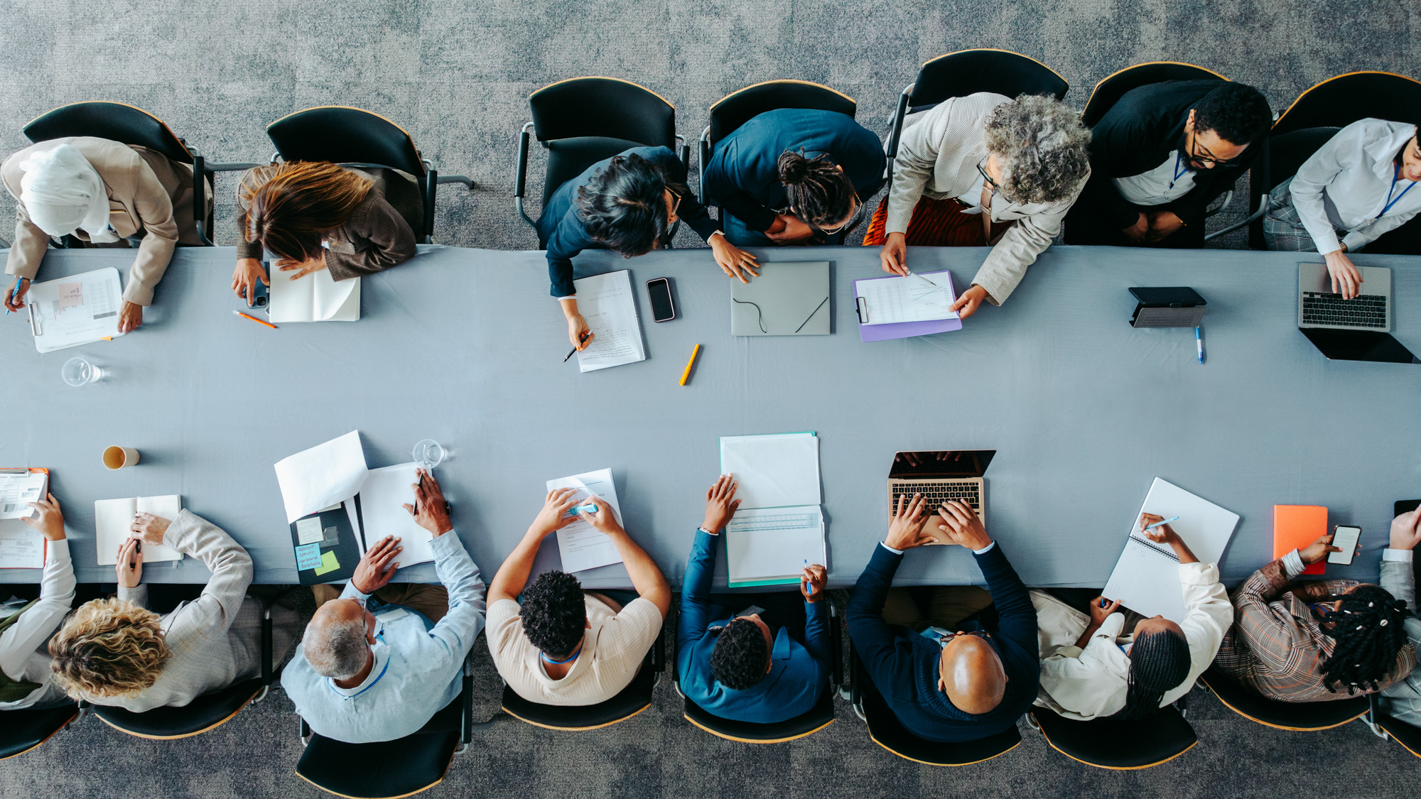 Bovenaanzicht van grote groep mensen die samenwerken aan tafel