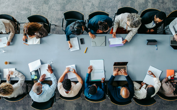 Bovenaanzicht van grote groep mensen die samenwerken aan tafel