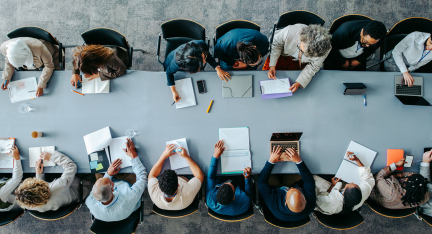 Bovenaanzicht van grote groep mensen die samenwerken aan tafel