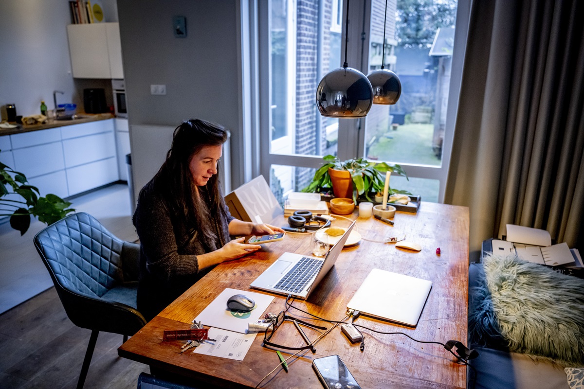 Een vrouw is aan het thuis werken in de woonkamer achter een computer