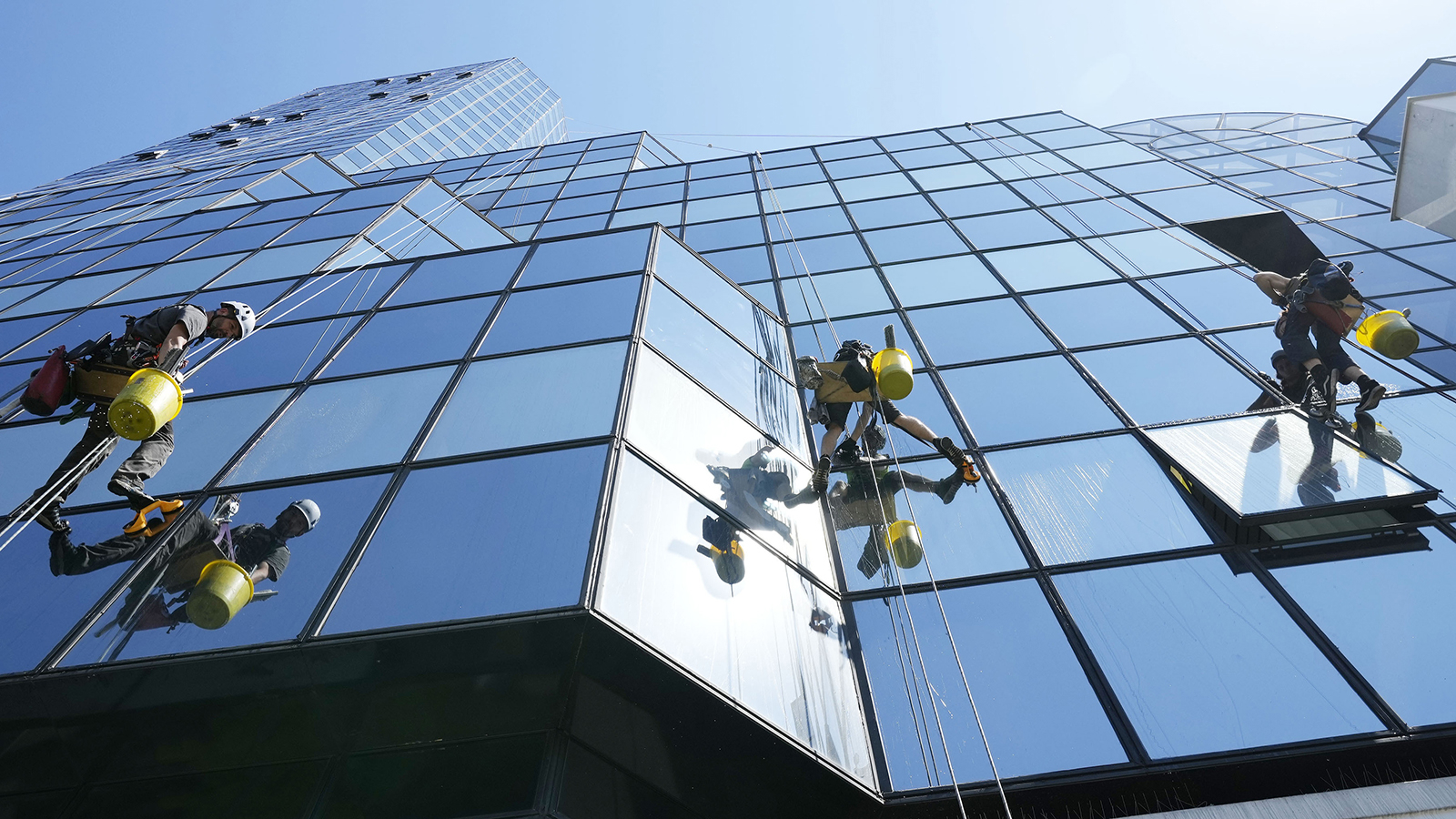 Glazenwassers bij kantoorpand hoog in de lucht