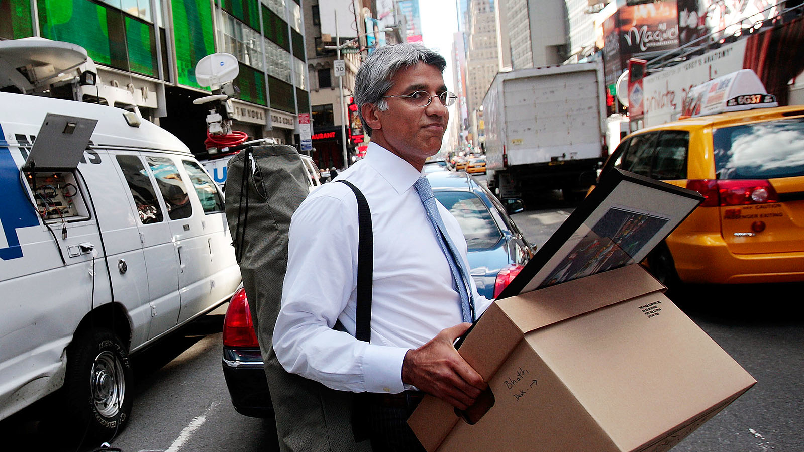 Man in drukke straat met doos in handen