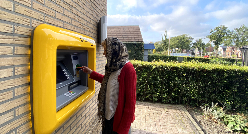 Persoon die geld pint bij een geldmaat