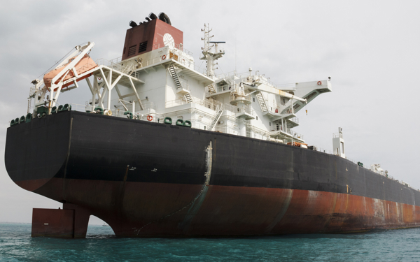 Een olietanker die dichtbij een aardolieterminal en offshore platform in Perzische Golf wordt verankerd.