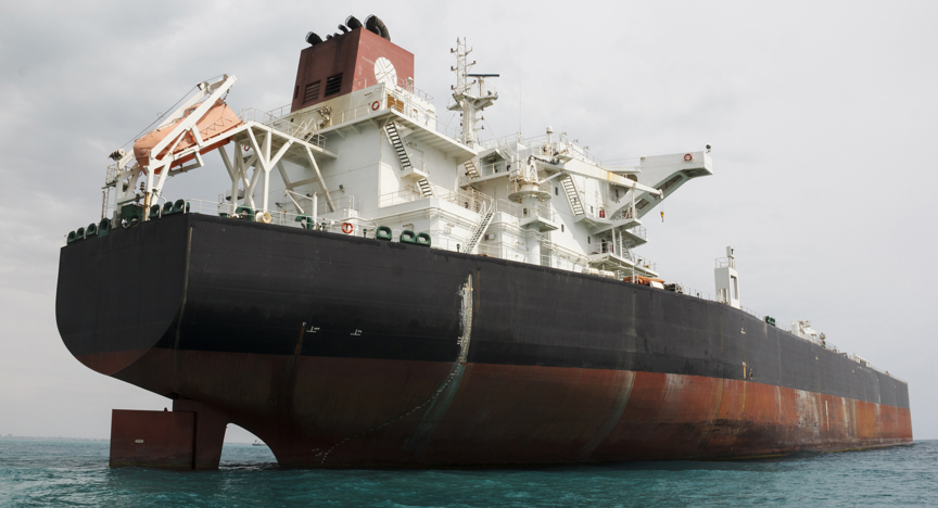 Een olietanker die dichtbij een aardolieterminal en offshore platform in Perzische Golf wordt verankerd.