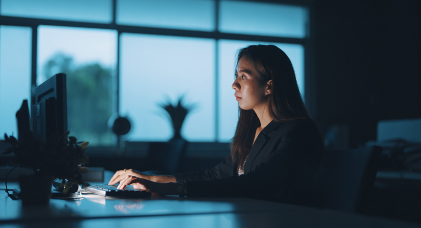 Vrouw werkt in het donker op een computer.