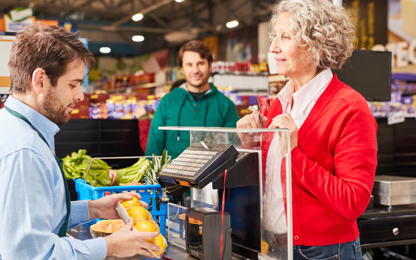 Vrouw die boodschappen afrekent bij een kassière in een winkel