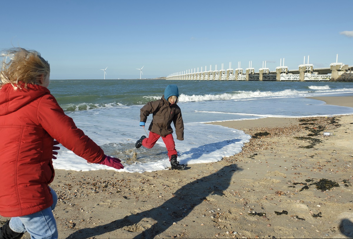 Kind aan strand met deltawerken
