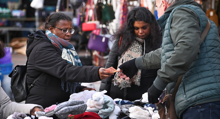 Vrouw koopt warme sokken op de markt, ze betaalt met contant geld