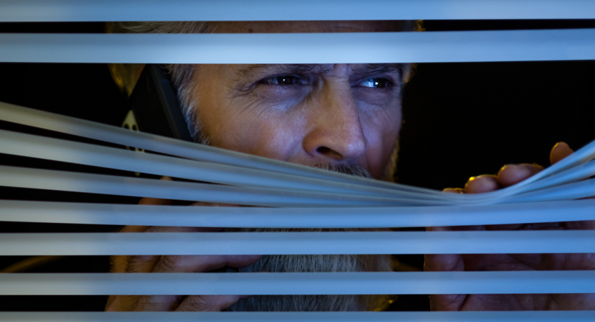 Detective kijkt door de raamverduistering naar buiten