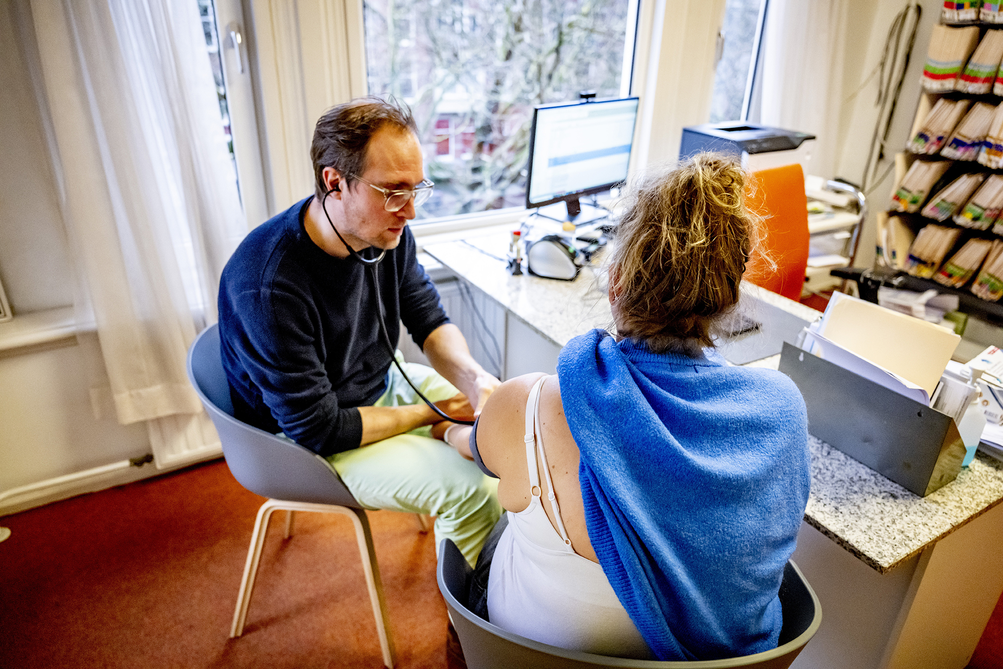 Een huisarts onderzoekt een patiënt tijdens een bezoek aan de huisartsenpraktijk 