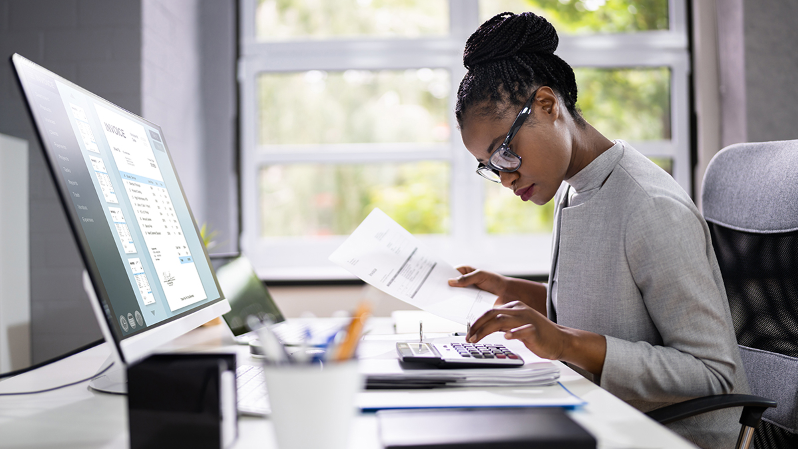 Vrouw met documenten achter laptop