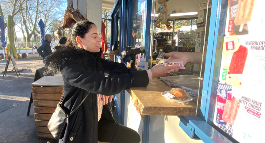 Een vrouw koopt iets met contant geld bij een kraam