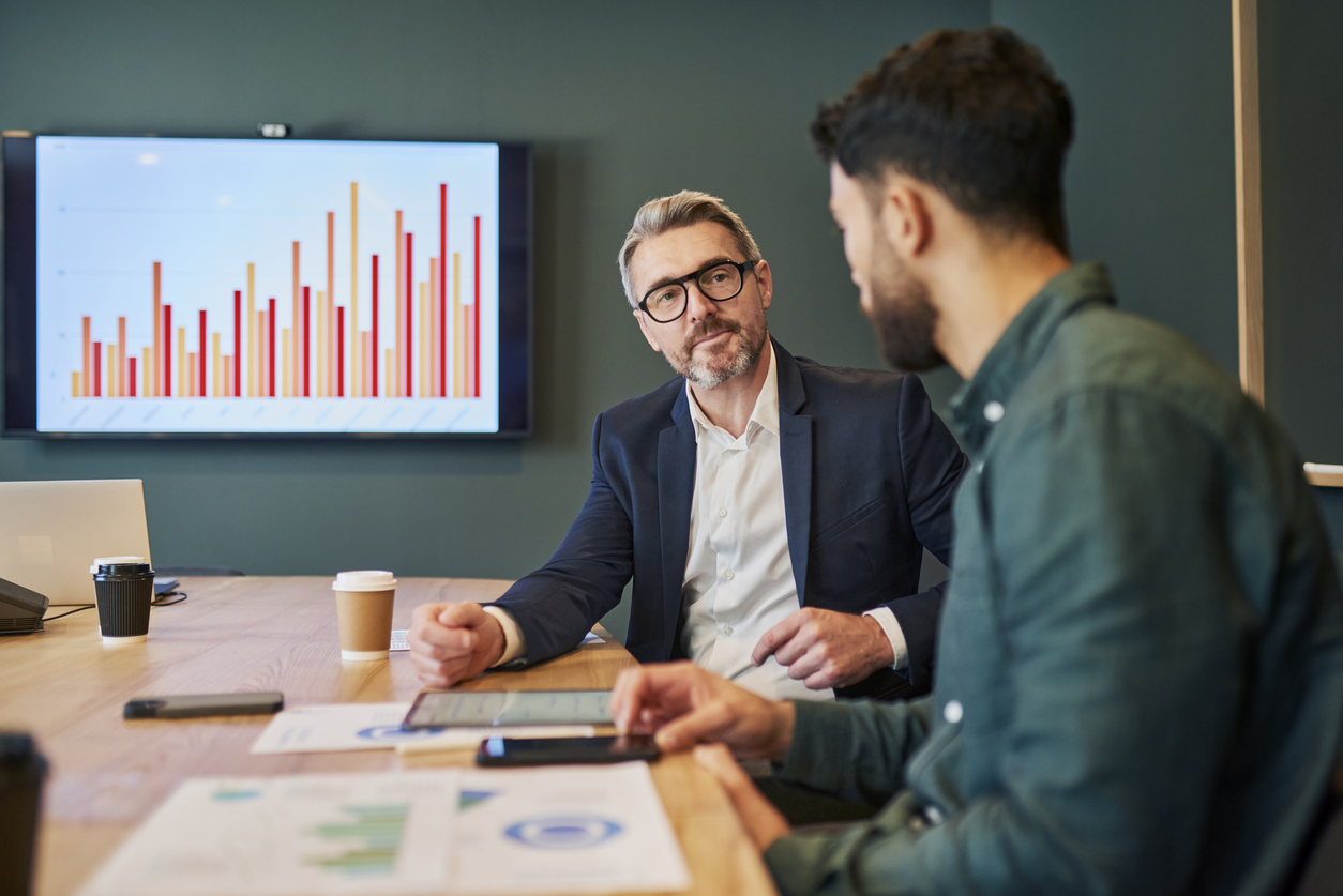 Twee mannen op kantoor achter laptops bespreken rapportage