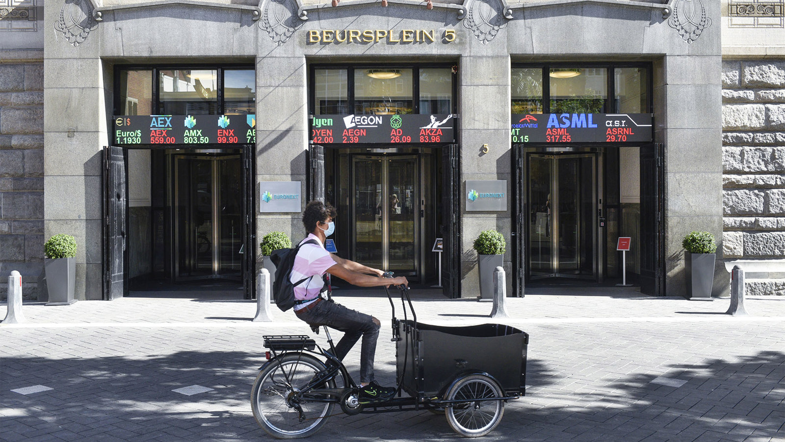 Een foto van een jongen die op een bakfiets voor Beursplein langsfietst Een foto van een jongen die op een bakfiets voor Beursplein langsfietst