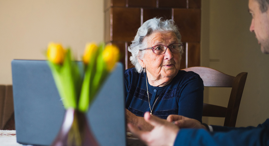 Oudere krijgt uitleg achter de computer