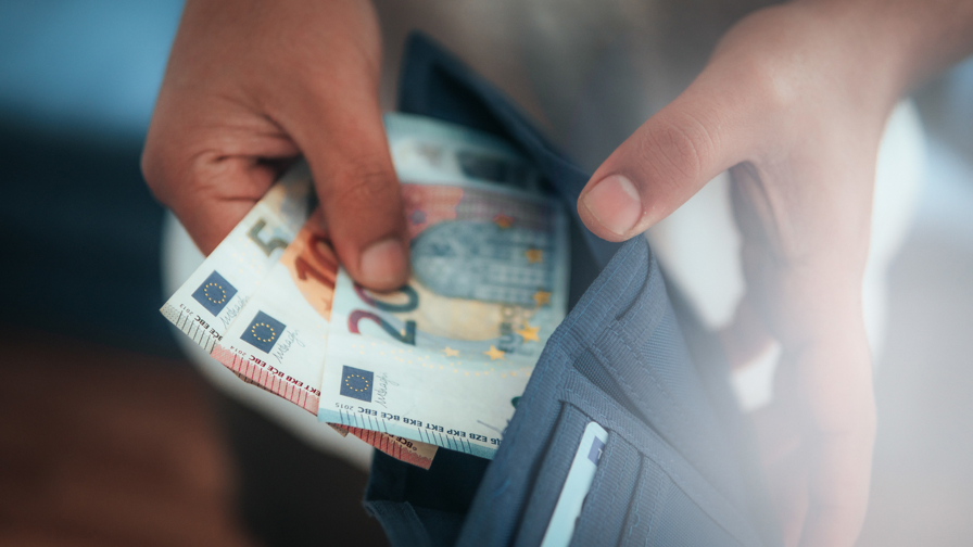 Close up van een portemonnee waar briefgeld uit gehaald wordt.