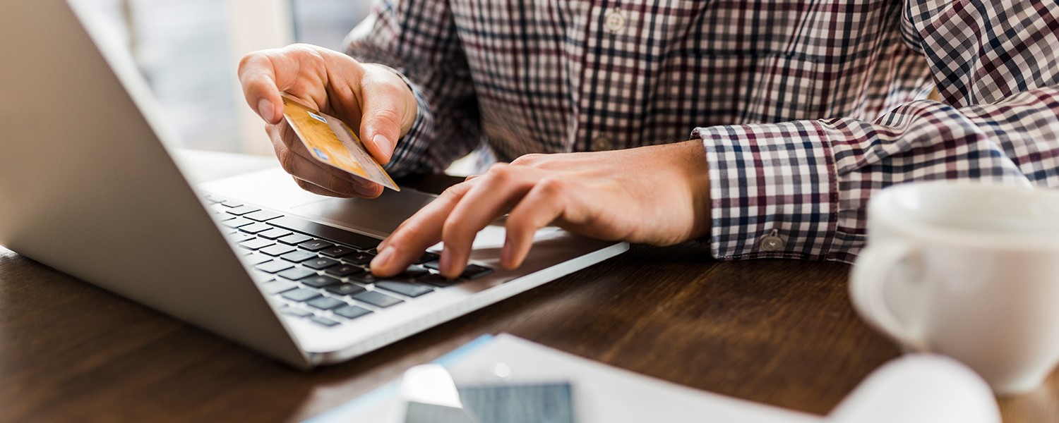 Iemand die online betaald achter een laptop met een bankpas
