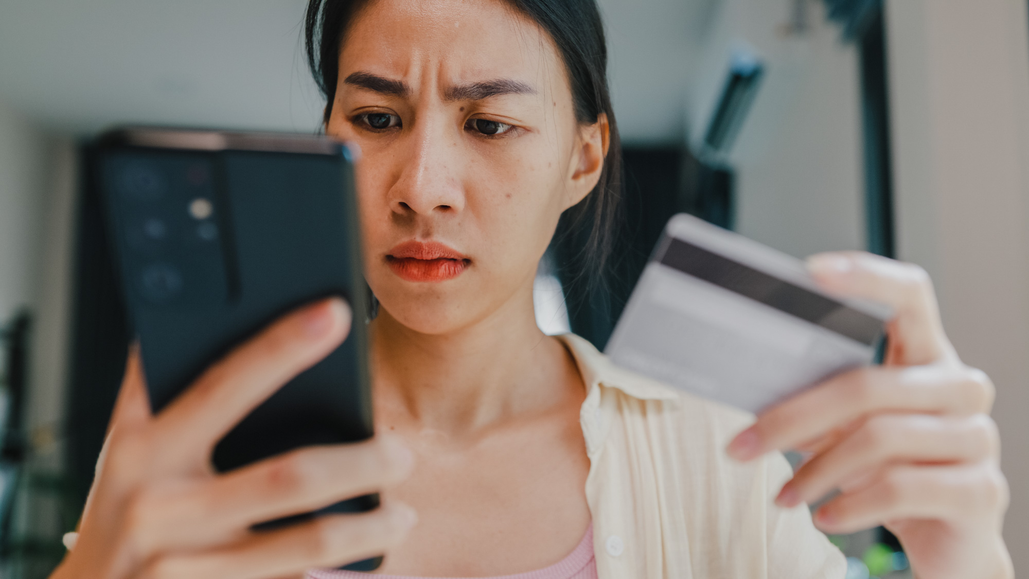 Een vrouw kijkt naar haar telefoon nadat ze erachter is gekomen dat zij het slachtoffer is van online fraude.