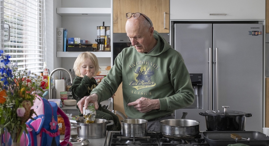 Opa en zijn kleindochter zijn samen aan het koken aan het fornuis