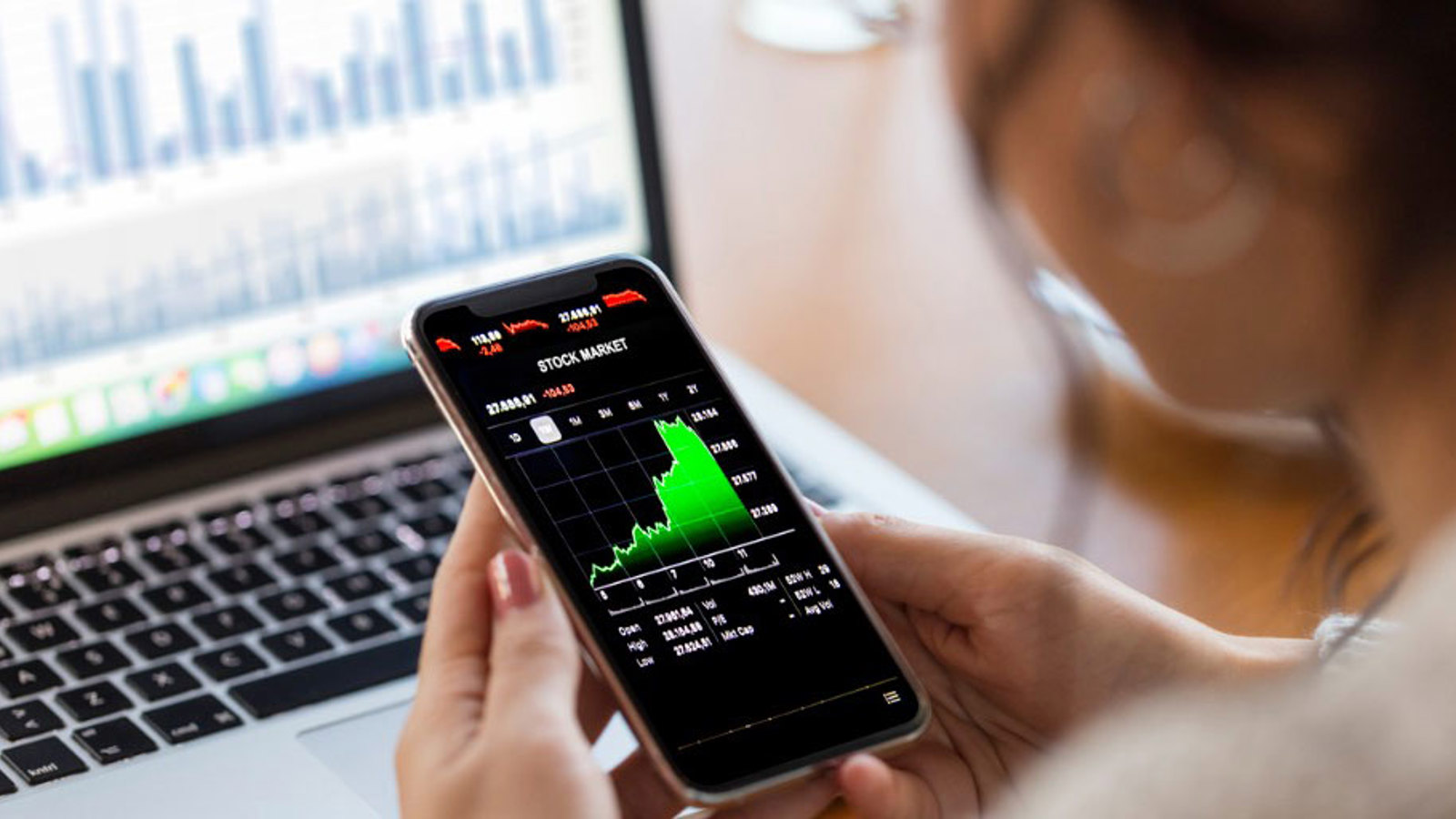 Financieel expert kijkt op telefoon naar grafieken Financieel expert kijkt op telefoon naar grafieken