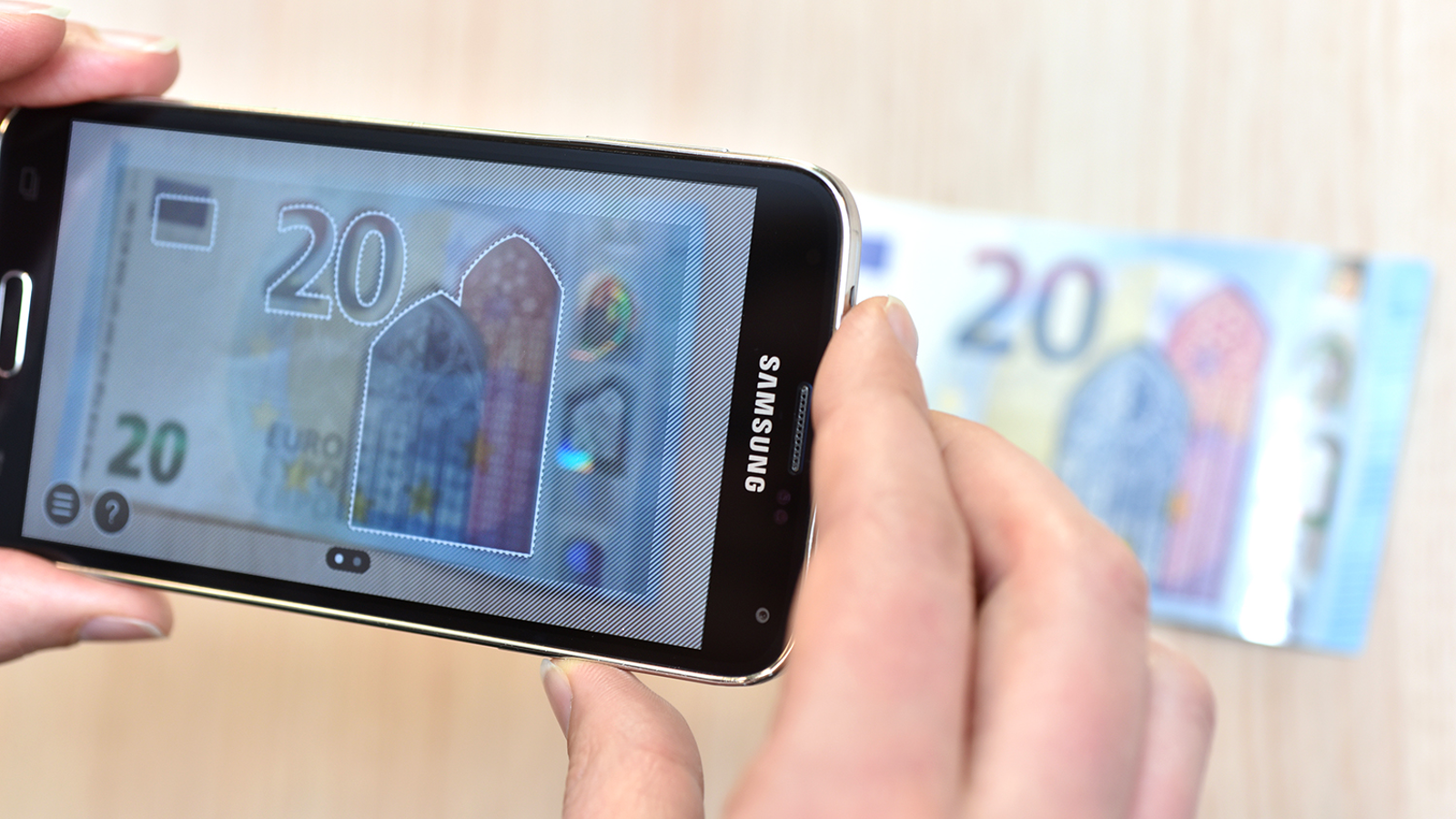 Een twintig eurobiljet wordt geverifieerd door een app op een telefoon Een twintig eurobiljet wordt geverifieerd door een app op een telefoon