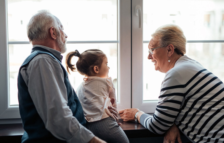 Grootouders kijken uit raam met kleinkind op schoot