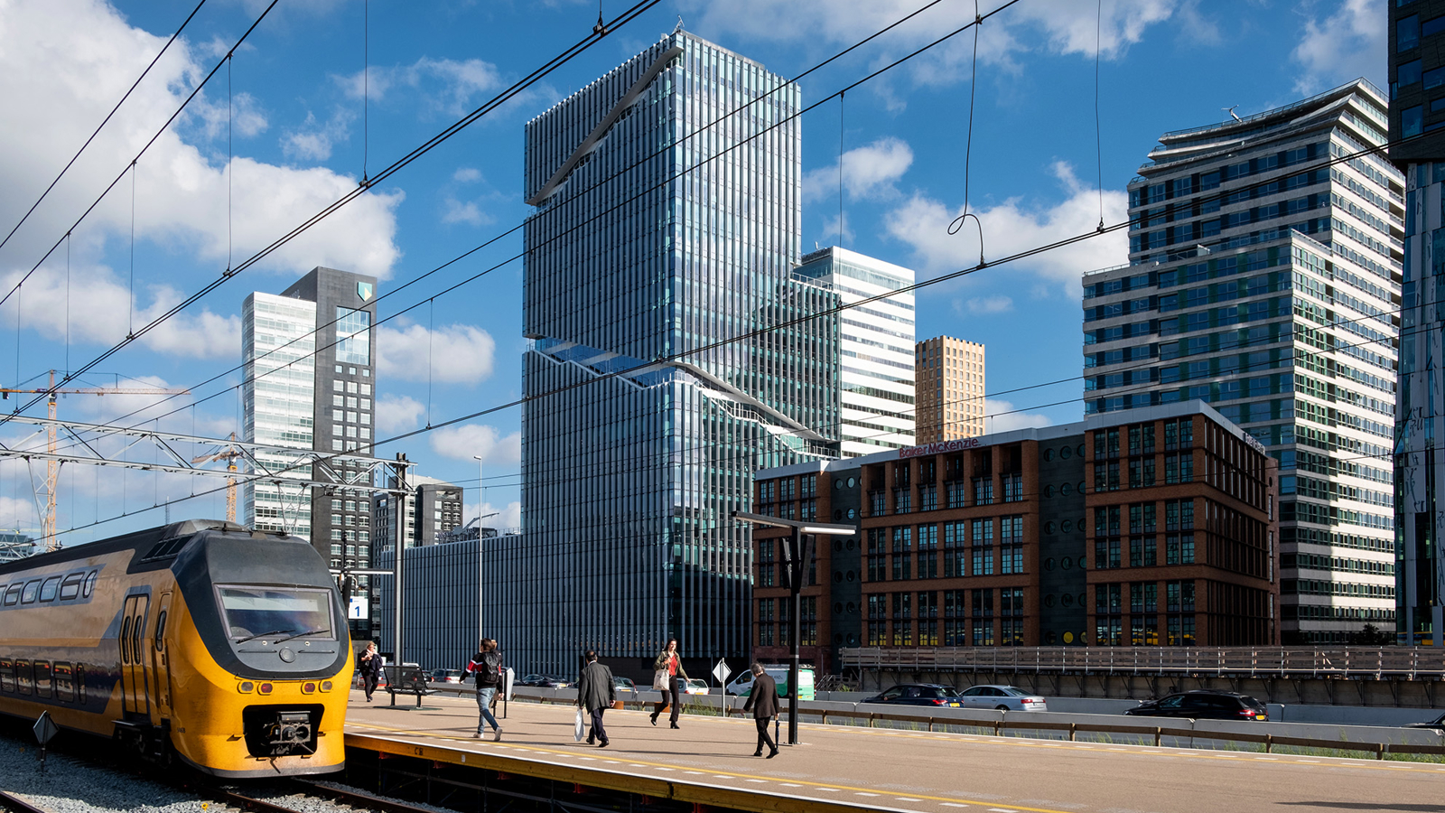 Treinstation nabij de zuidas met links een NS trein en rechts skyscrapers