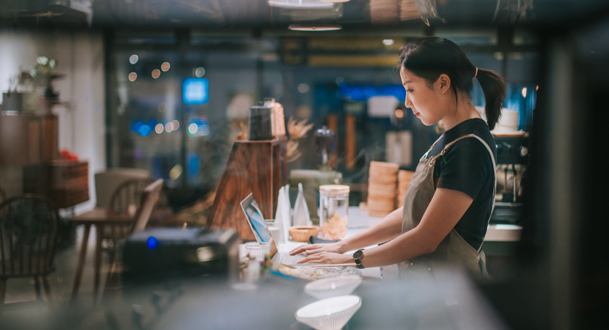 Eigenaar van een koffiezaak doet haar bankzaken op een laptop.