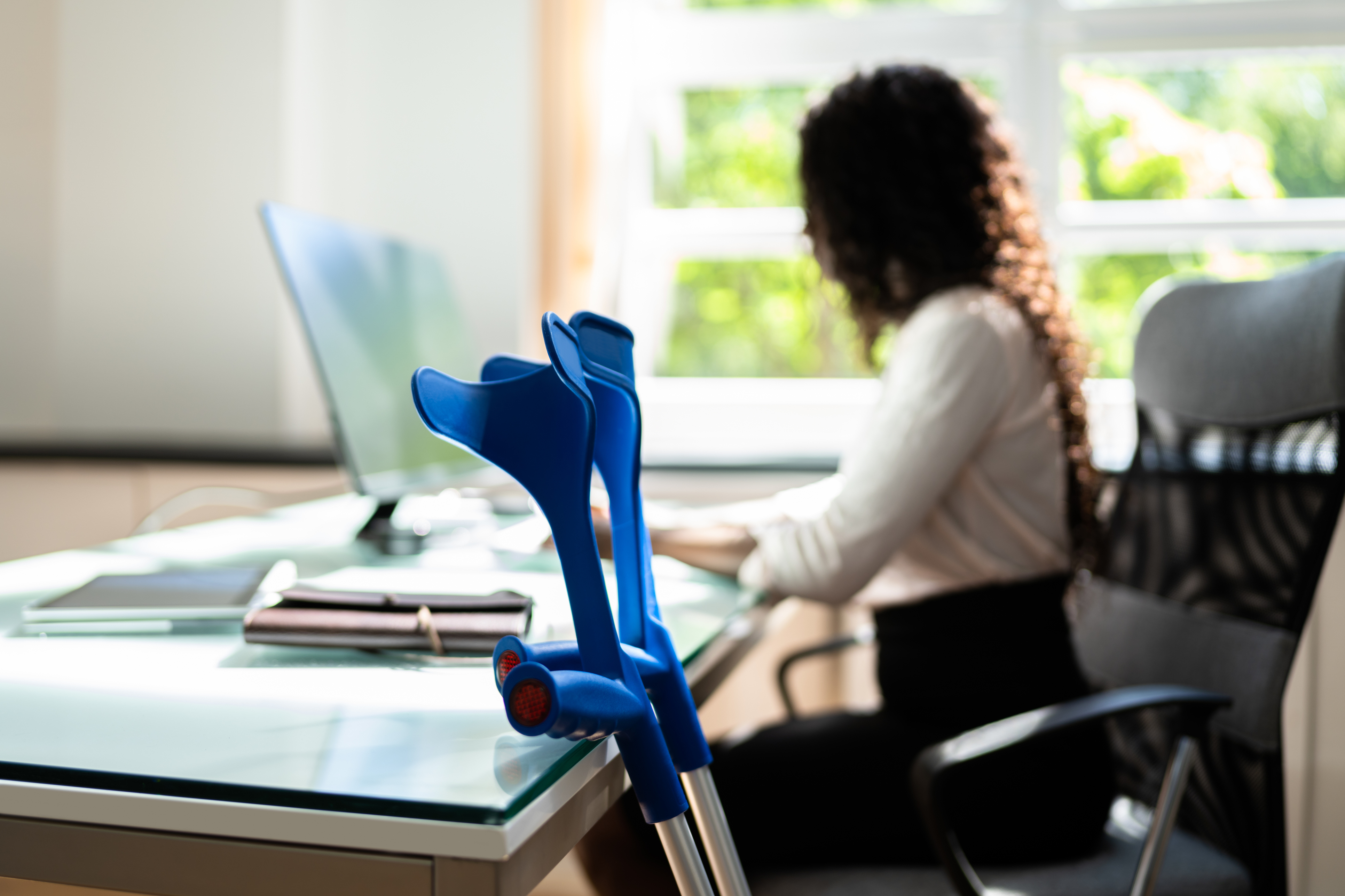 Medewerker met krukken achter een bureau