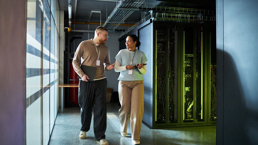 Collega’s discussiëren over werk wandelend  in een server ruimte