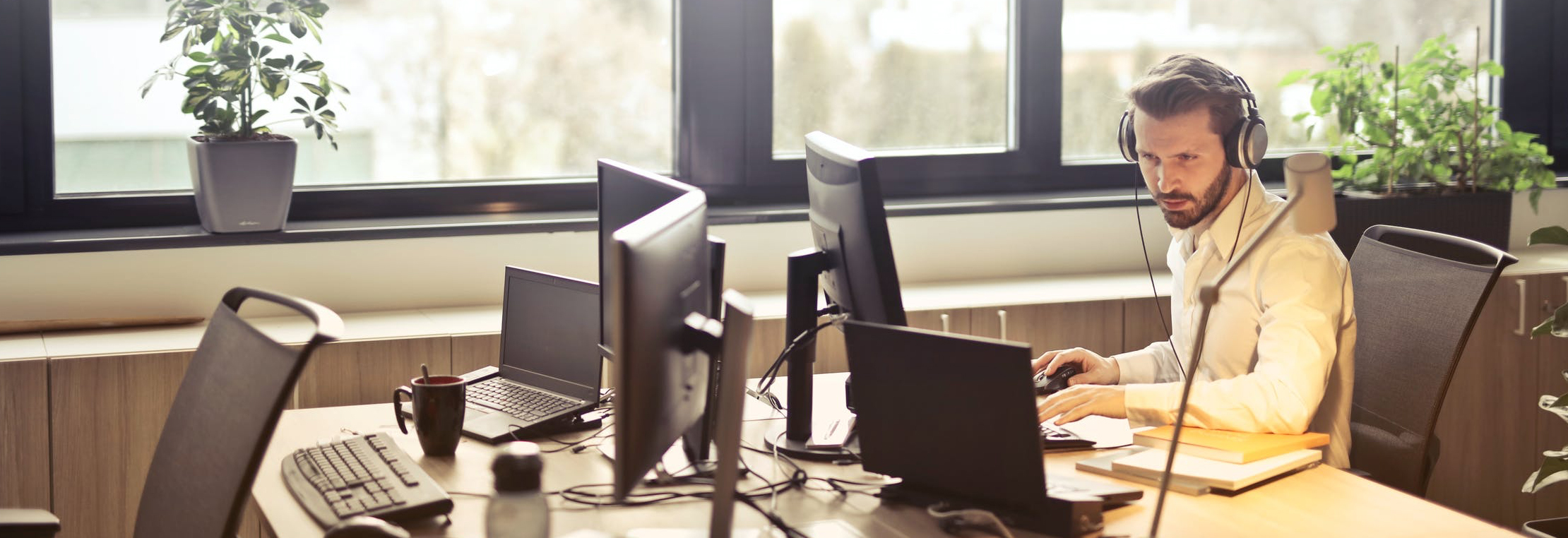 Man die werkt op een kantoor met veel pc's en een laptop