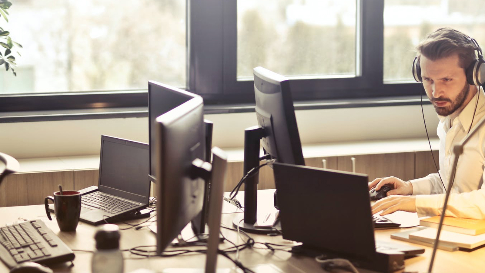 Man die werkt op een kantoor met veel pc's en een laptop